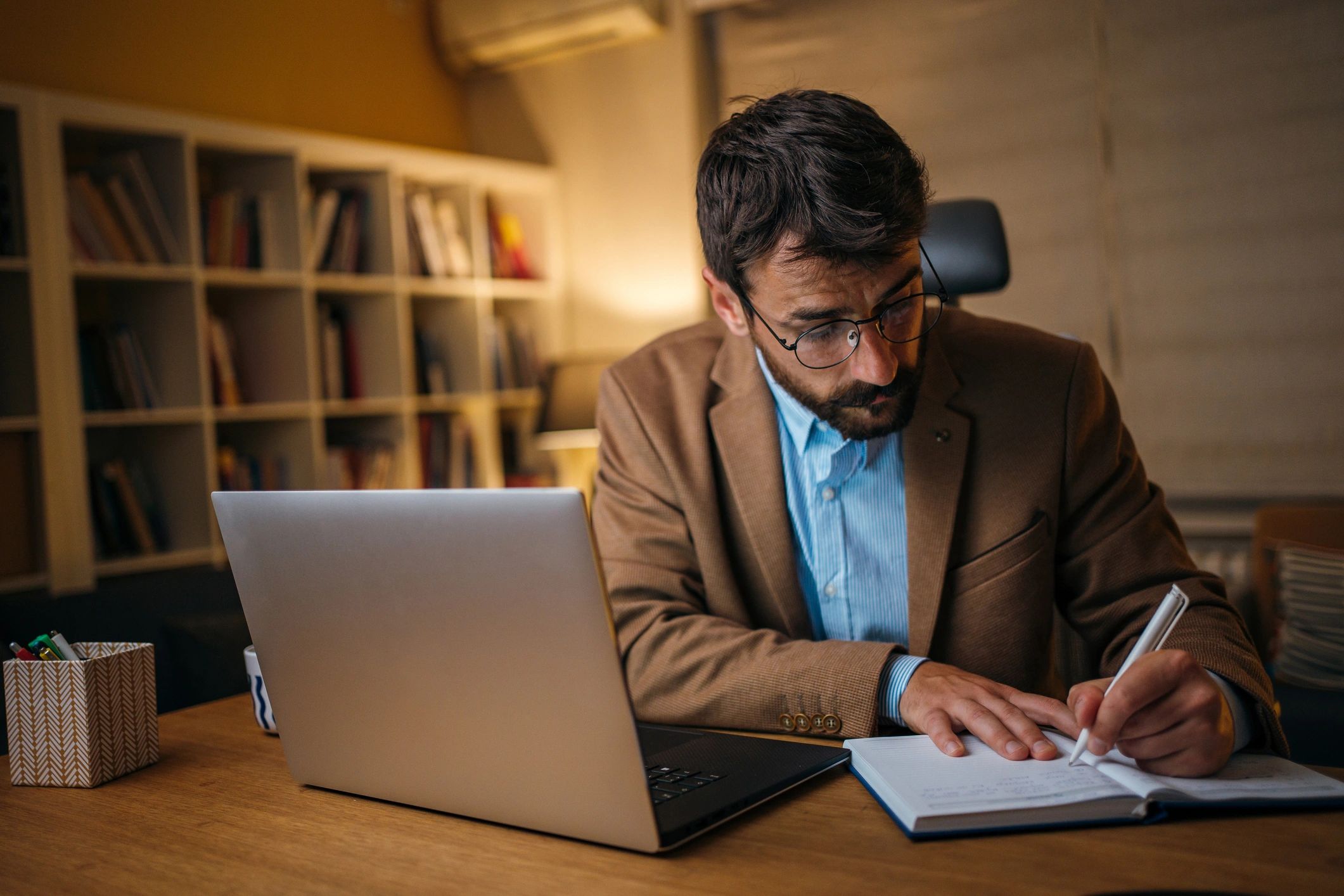 Reporter researching on a laptop and taking notes