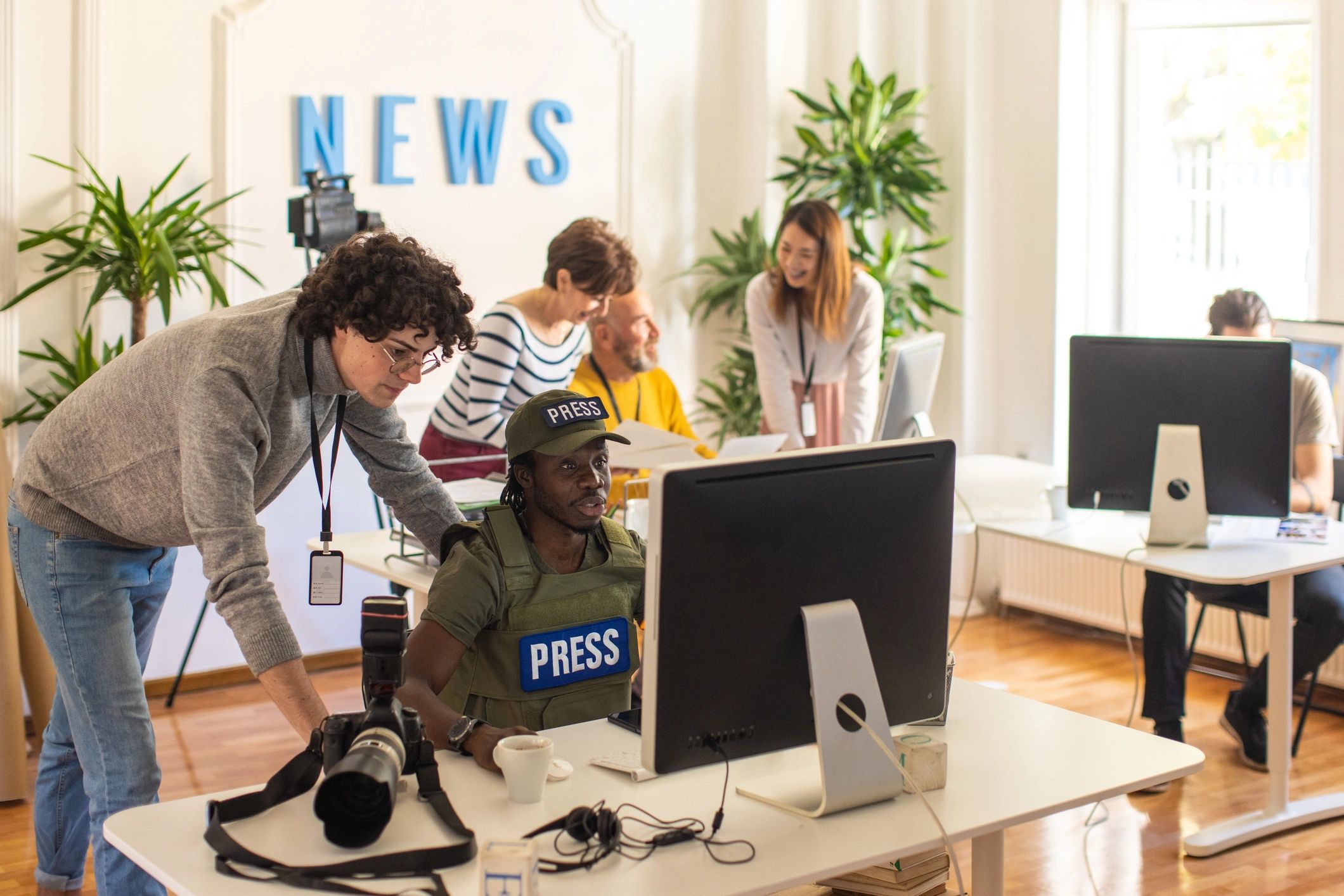 Editorial team collaborating at computers in a newsroom