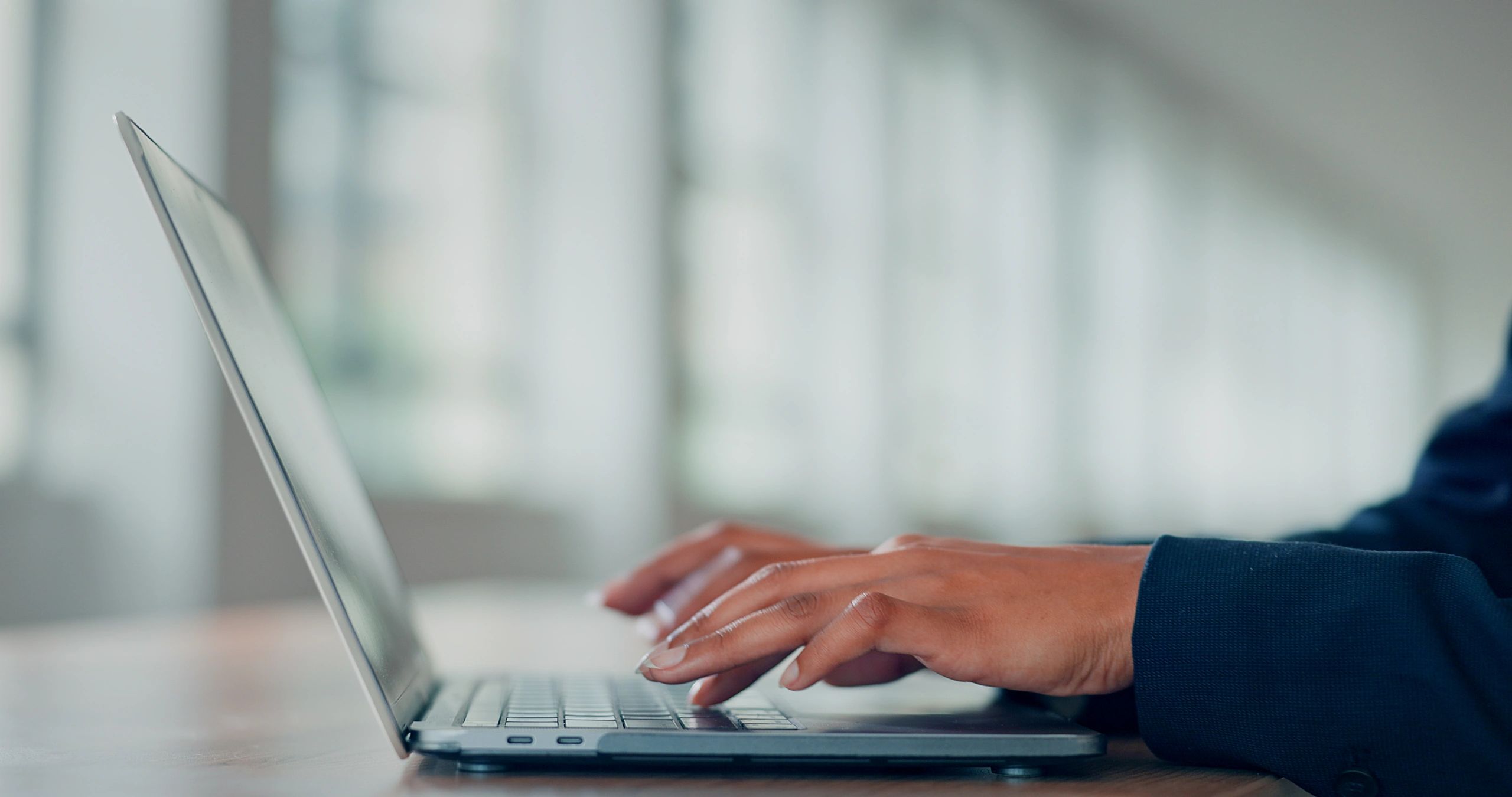Hands typing on a laptop